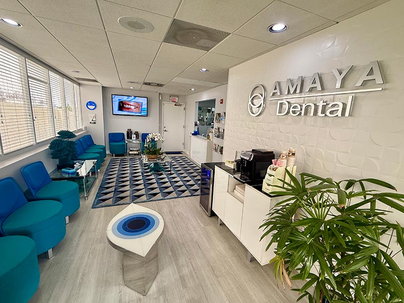 This image shows an interior space with modern furnishings, including a reception area with a sign for AMAYA DENTAL on the wall, indicating that this is likely a dental clinic s waiting room.
